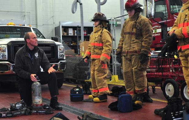 A firefighter demonstrates equipment for high school students
