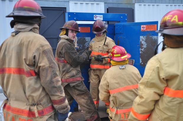 A firefighter demonstrates equipment for high school students