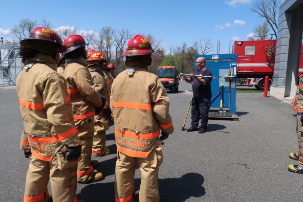 Firefighter demonstrates the use of a Halligan for high school students
