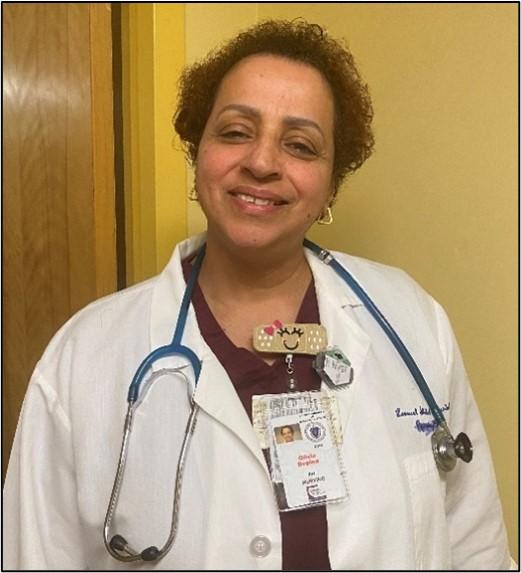 Olivia Depina is a registered nurse and she is in a white lab coat smiling at the camera. She looks very friendly.