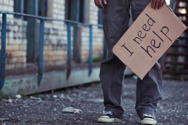 Young Person in sneakers holding a sign that says “I need help”