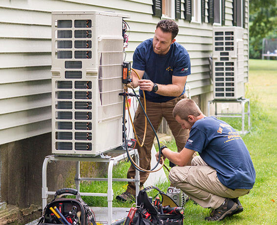 two men working on a heat pump