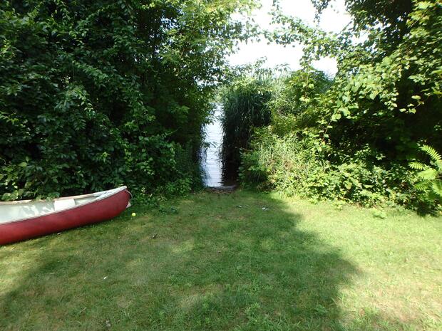 small gap in the bushes with narrow path to water