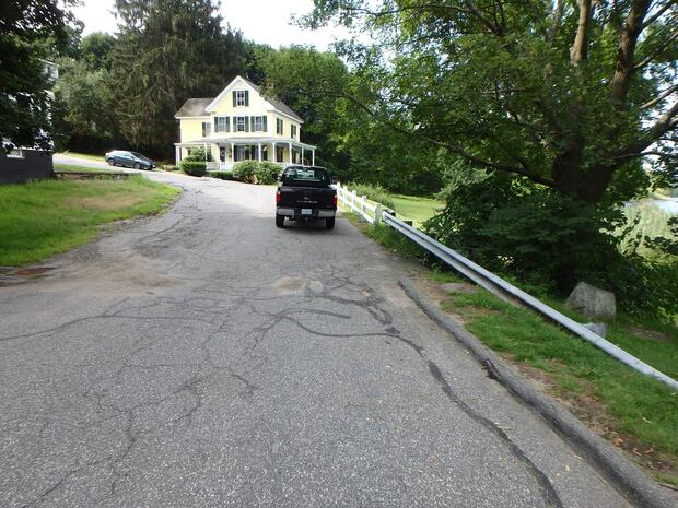 parking along the roadside in front of a house with guard rail to right