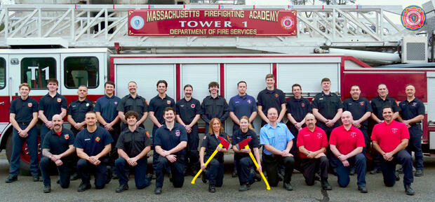 Photo of 25 firefighters on and around a ladder truck