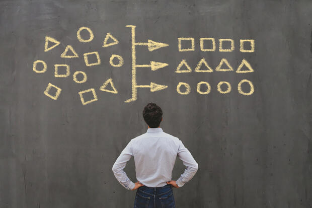 man looking at blackboard with shapes.