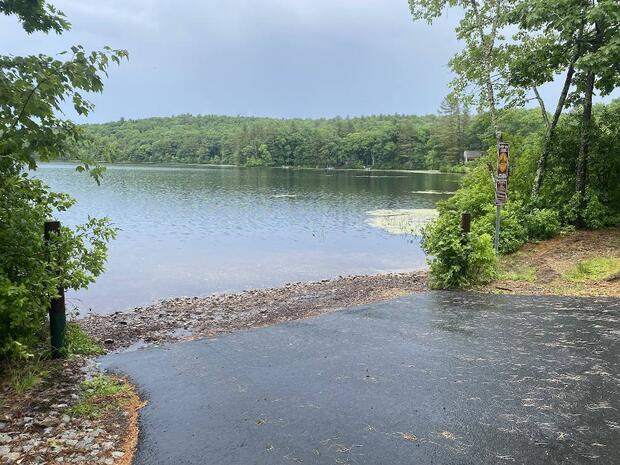 close up of paved ramp giving way to gravelly shoreline at waters edge