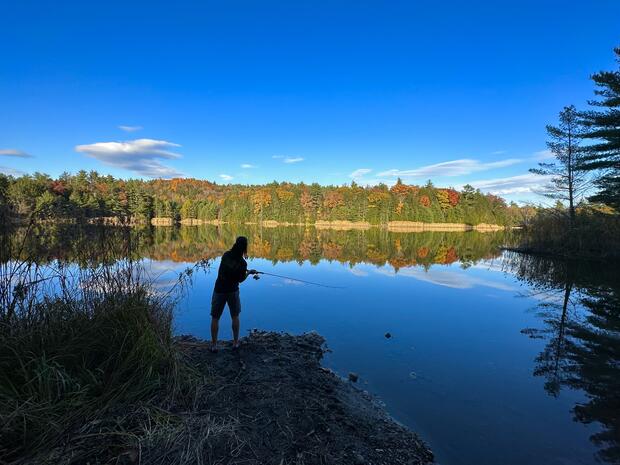 Person fishing with fall foliage