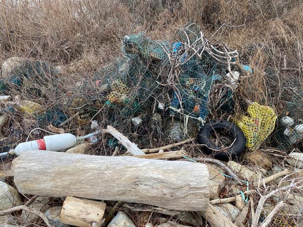 A tangled mass of derelict fishing gear and other debris on a rocky shore.