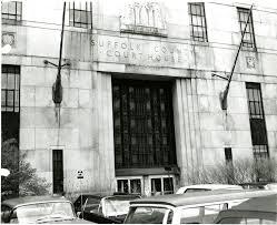 Exterior of Suffolk County Courthouse with parked cars in front.