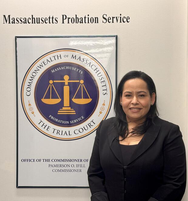 A person stands in front of the Massachusetts Probation Service emblem and text.