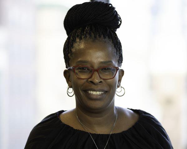 Debra with a bun hairstyle, glasses, and wearing a black top