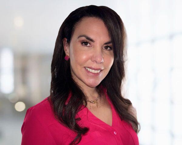 Heatha smiling with long hair, and with a red top