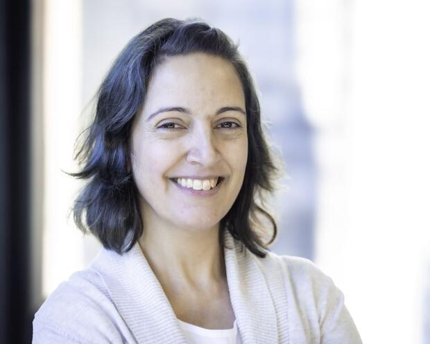 Nealia smiling in front of a window, wearing white top