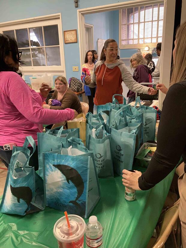 People gathered in a room around a table with dolphin-themed bags.