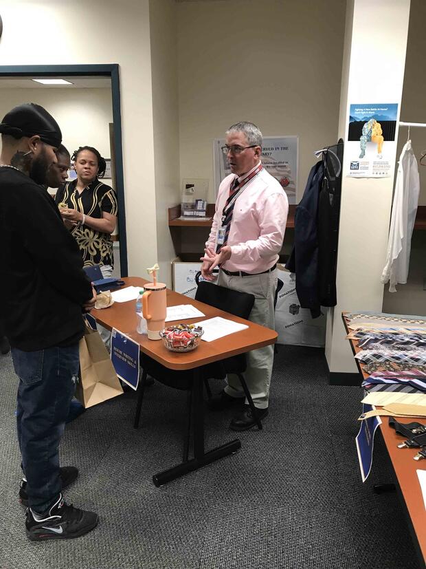 People gathered around a table in an office, with papers and a bowl of candies on the table.