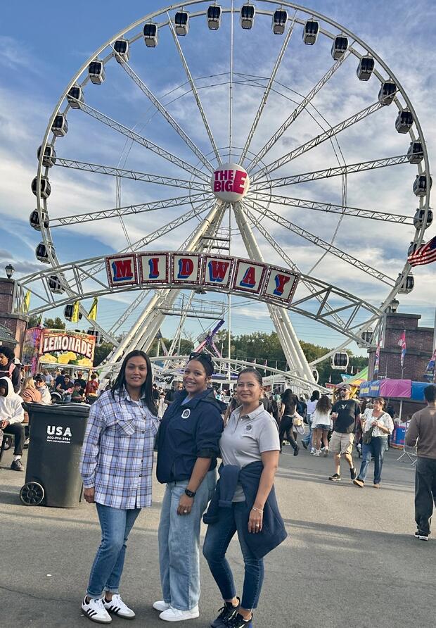 Three probation employees pose in front of a ferris wheel at the Big E