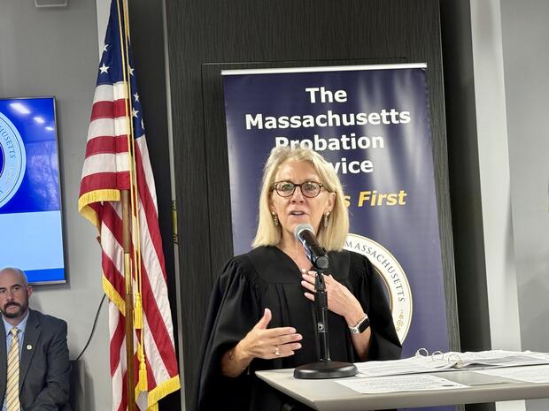 A woman in a judge's robe speaking at a podium.