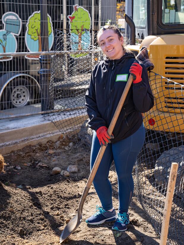A smiling woman, holding a shovel