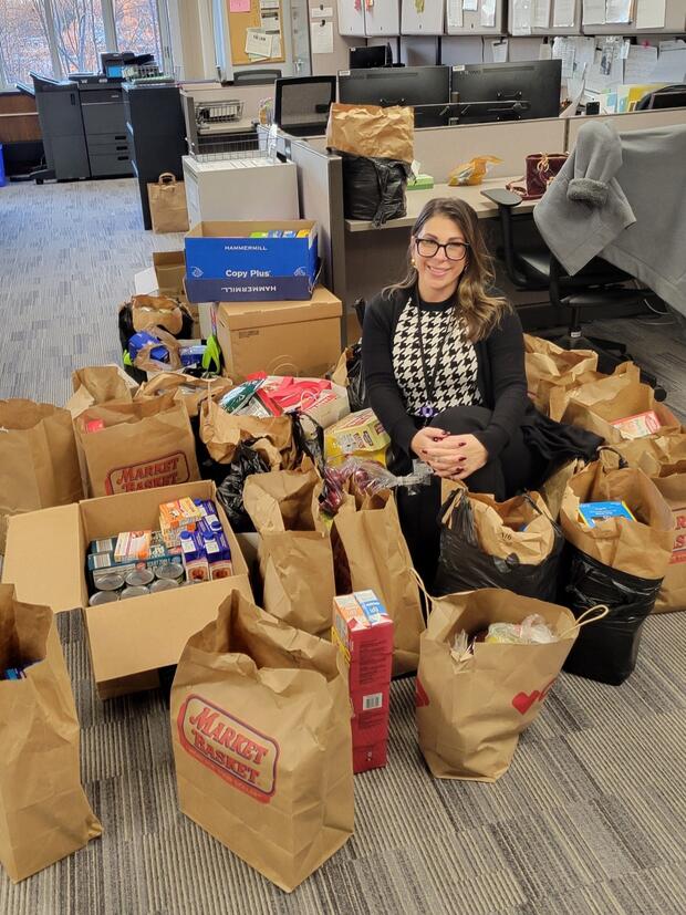A woman sits with a large pile of food donations
