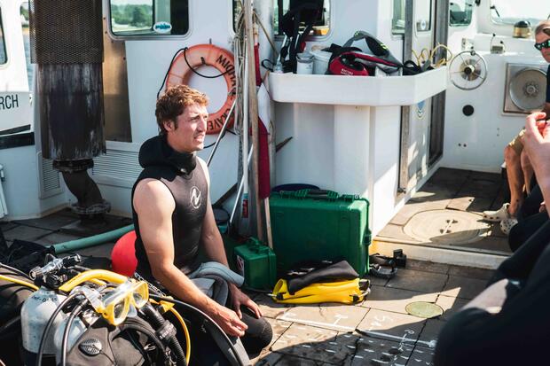 A scientific diver sits on the deck of a boat between eelgrass dives. 