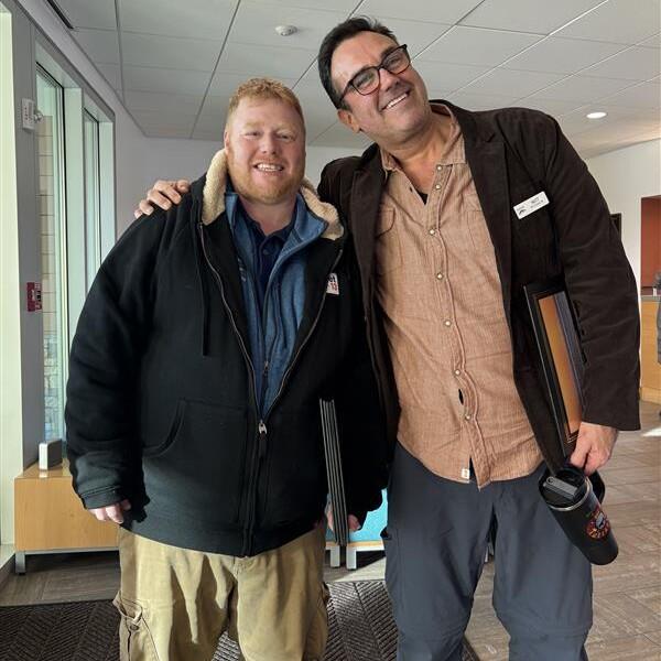 Two men standing together smiling.