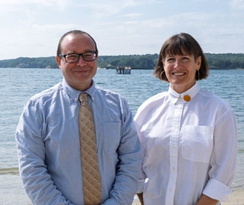 Women in white shirt stands next to man in blue shirt. 