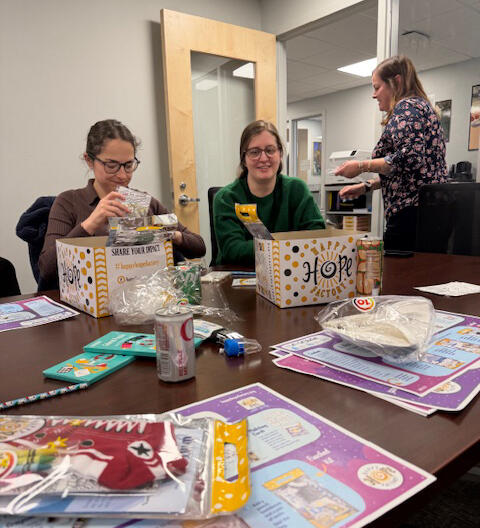 Three people assembling care packages in a conference room.