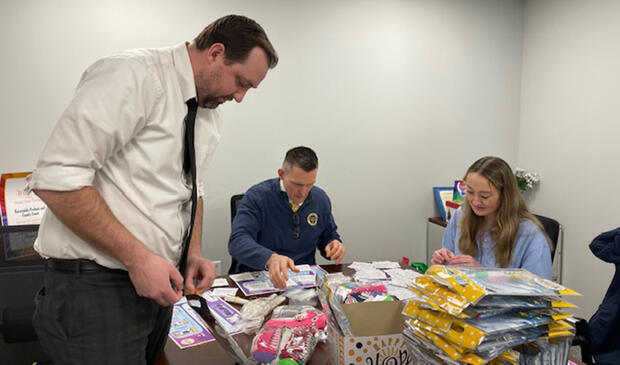 Three people assembling care packages in a conference room.