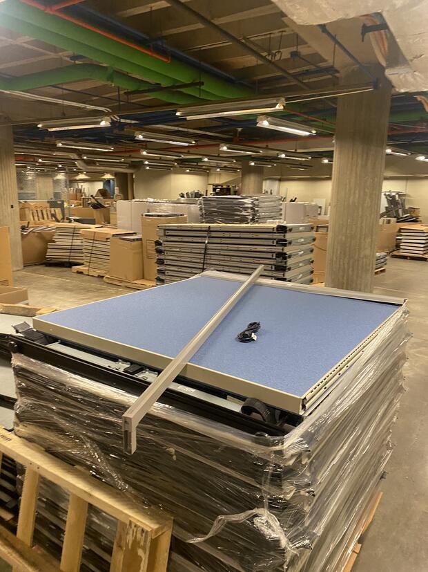 Picture of cubicle walls stacked on a wood palette in a warehouse. 