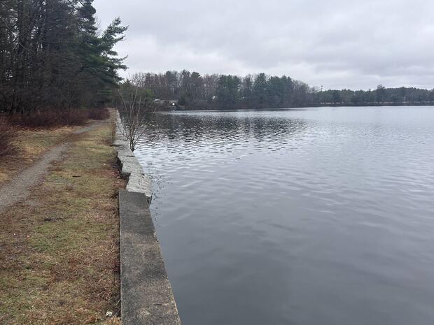 shoreline of northern basin of Lake Cochituate with low masonry wall where one can go shore fishing