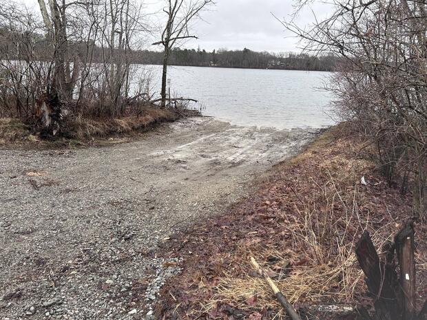 gravel and dirt boat ramp terminating into heard pond