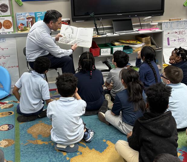 A person reading a book to children in a classroom.
