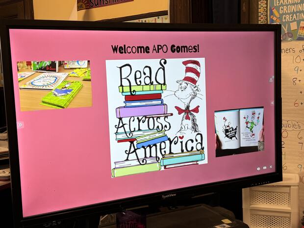 A monitor displaying a sign for Read Across America and The Cat in the Hat 
