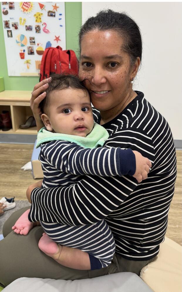 a photo of a dark-haired woman holding an infant
