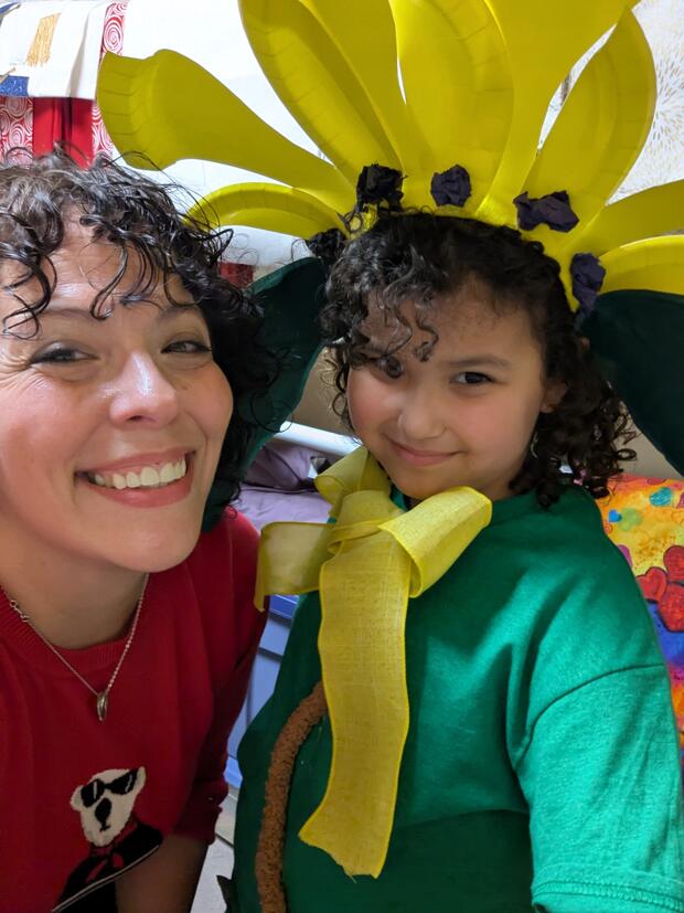 a woman smiling with a child wearing a sunflower headpiece