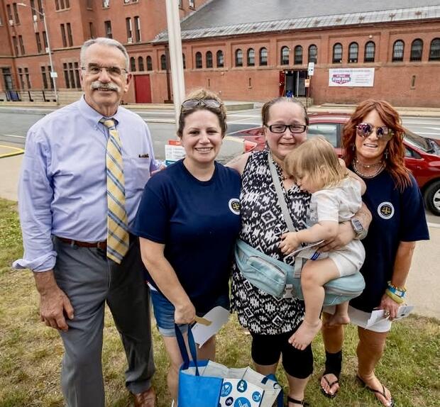 Four people and a toddler at an outdoor event.