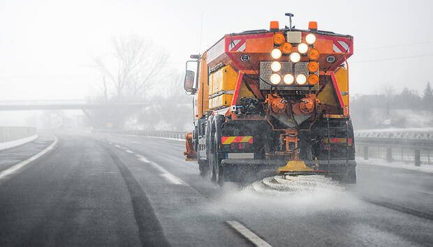 Snow plow salting street in winter time.