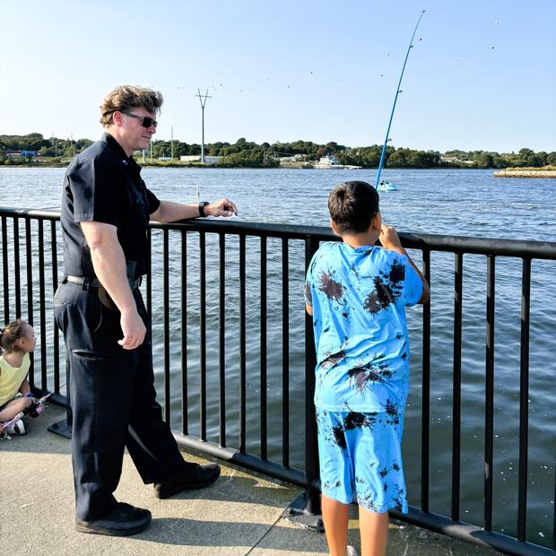 A policeman and young angler fishing from the shore.