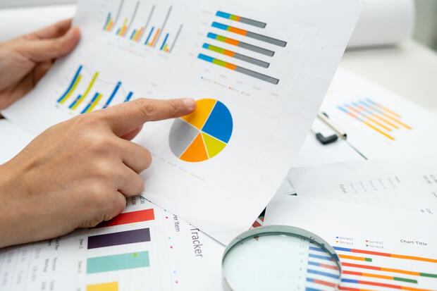 hands pointing at colorful data pie charts and graphs