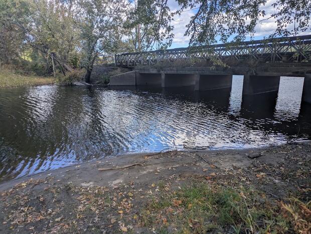 shallow sloping shoreline leading to waters edge near bridge