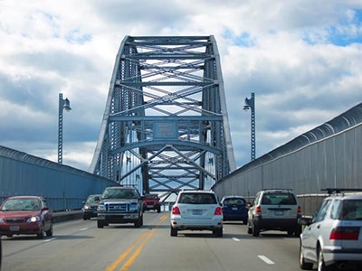 A view of cars traveling over one of the Cape Cod Bridges on a cloudy day.